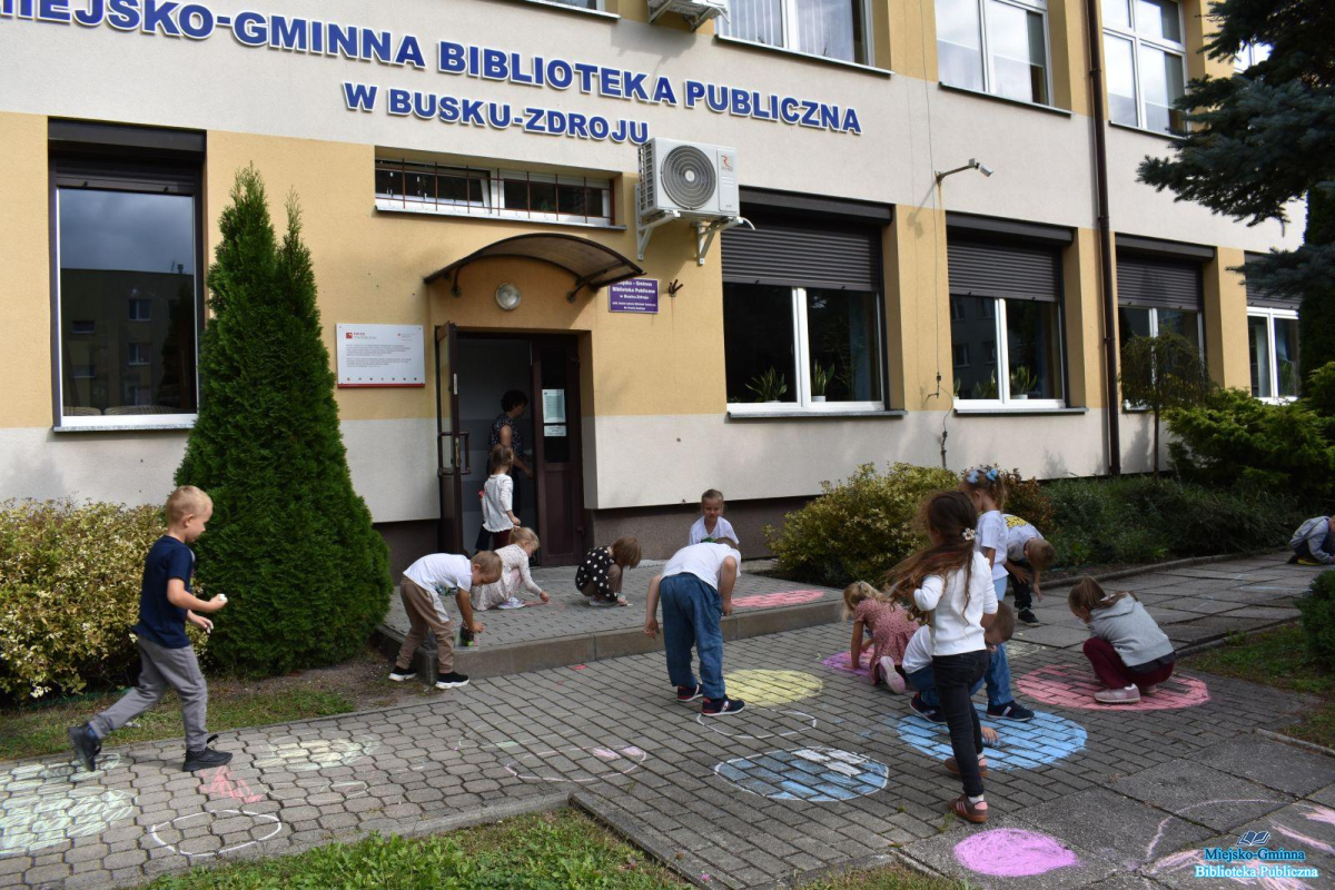 Dzieci kolorują chodnik przed budynkiem Dzieci kolorują chodnik przed budynkiem