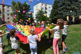 Grupa dzieci trzepocze chustą animacyjną.