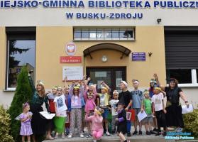 Grupa-dzieci-i-pa-pozuje-do-zdjcia-przed-budynkiem-biblioteki-podnoszc-rce-do-gory