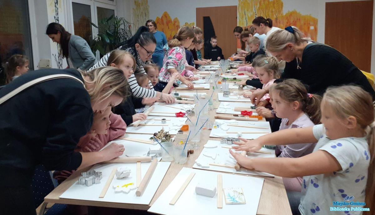 dzieci z rodzicami wykonują prace z gliny przy stoliku dzieci z rodzicami wykonują prace z gliny przy stoliku